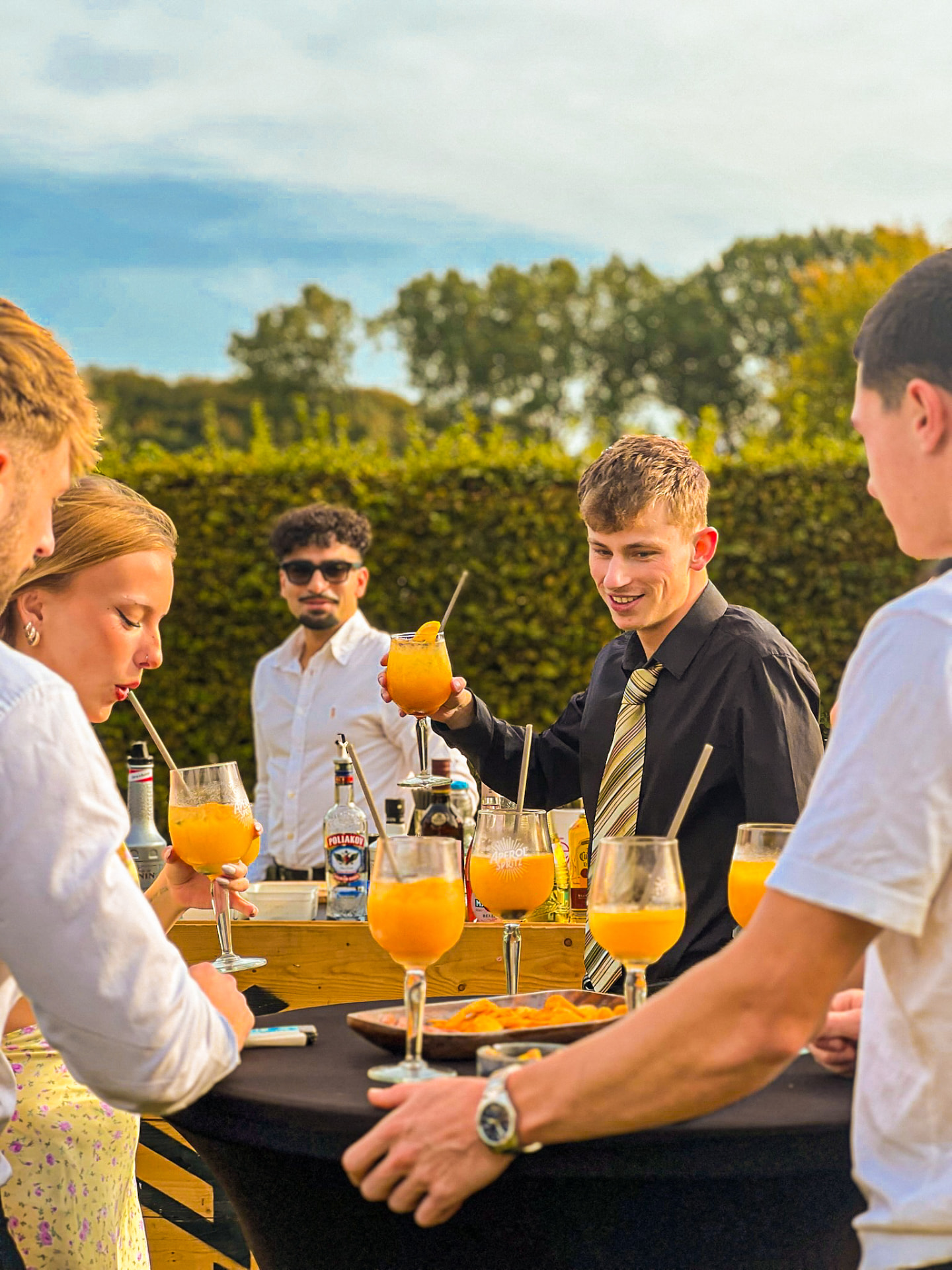 Invités réunis autour de leurs cocktails lors d'une réception en extérieur