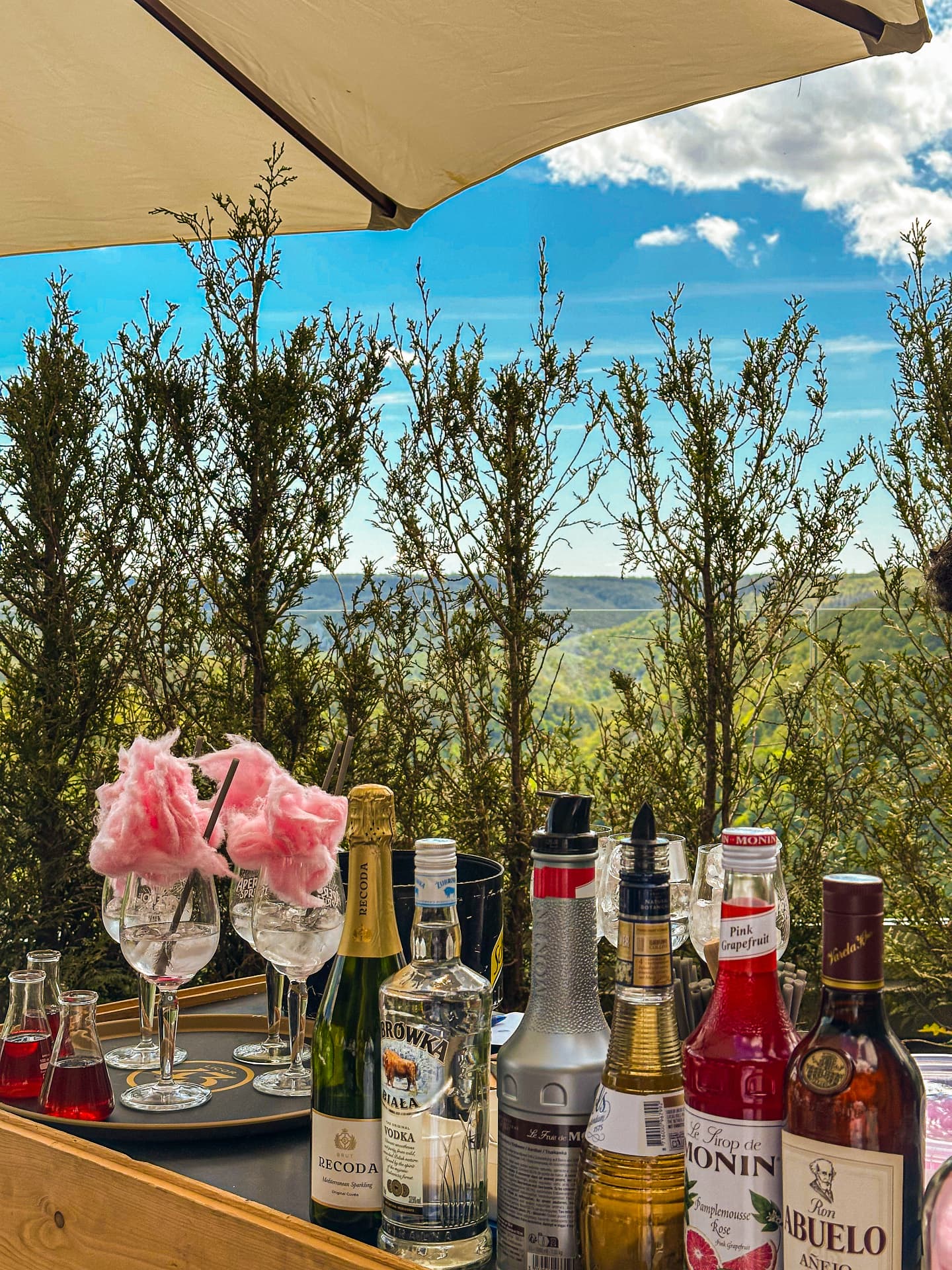 Bar mobile avec cocktails, bouteilles et barbe à papa rose sur une terrasse ensoleillée