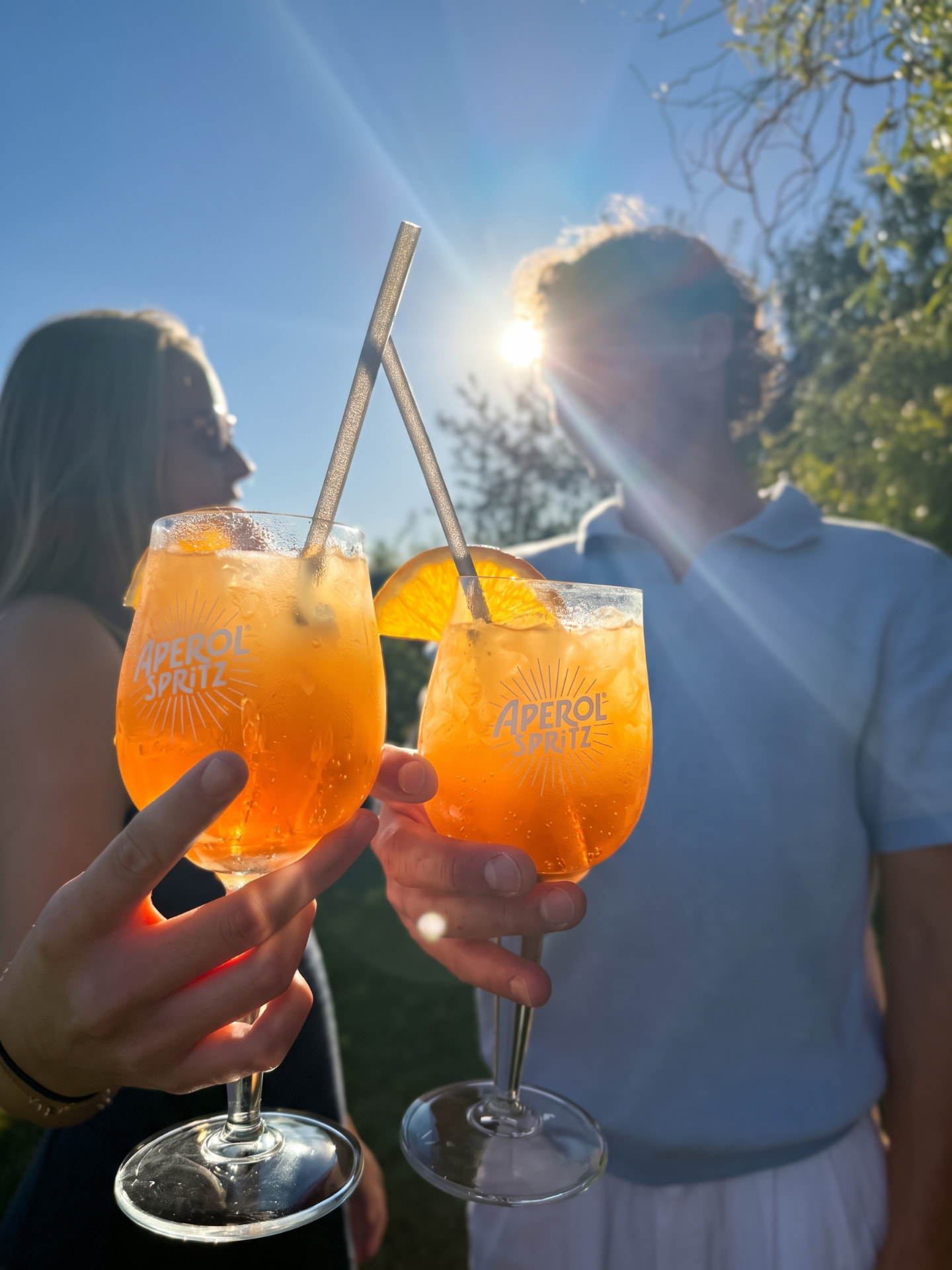 Deux invités trinquant avec des cocktails Spritz au soleil lors d'un événement privé