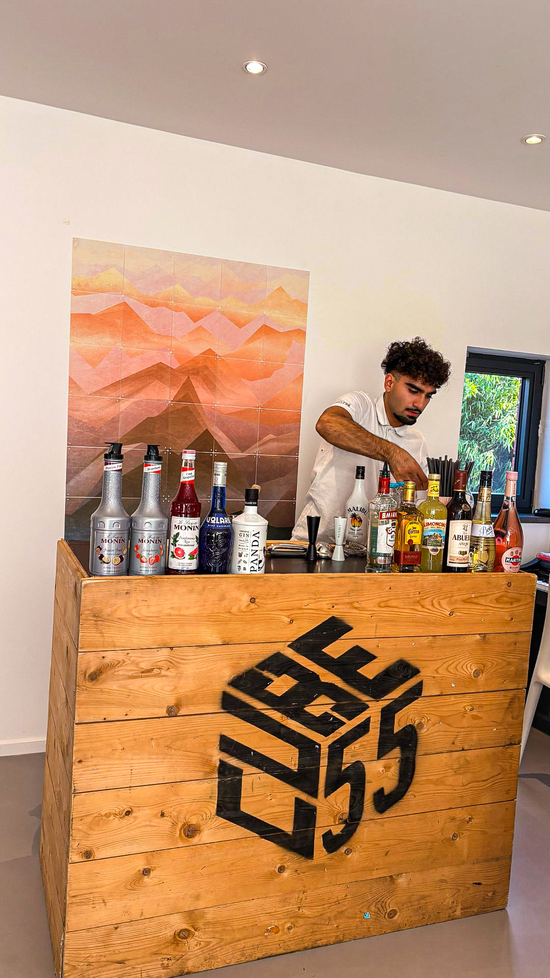 Barman préparant des cocktails derrière un bar en bois pour un afterwork d'entreprise
